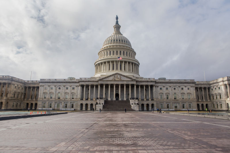 A view of the entrance of the Capitol Building against clouds.