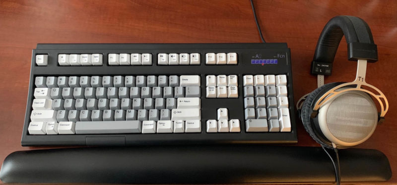 A keyboard sits next to an expensive set of headphones.