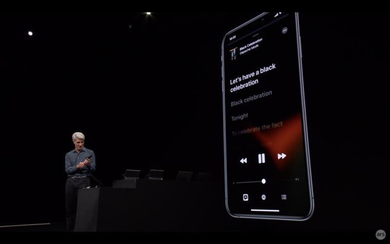 Apple Senior VP Craig Federighi on stage, showing an iPhone with iOS 13's dark mode.
