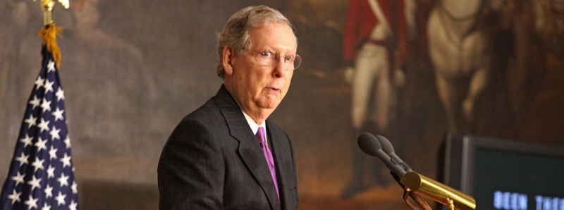 A man in a suit stands a podium.