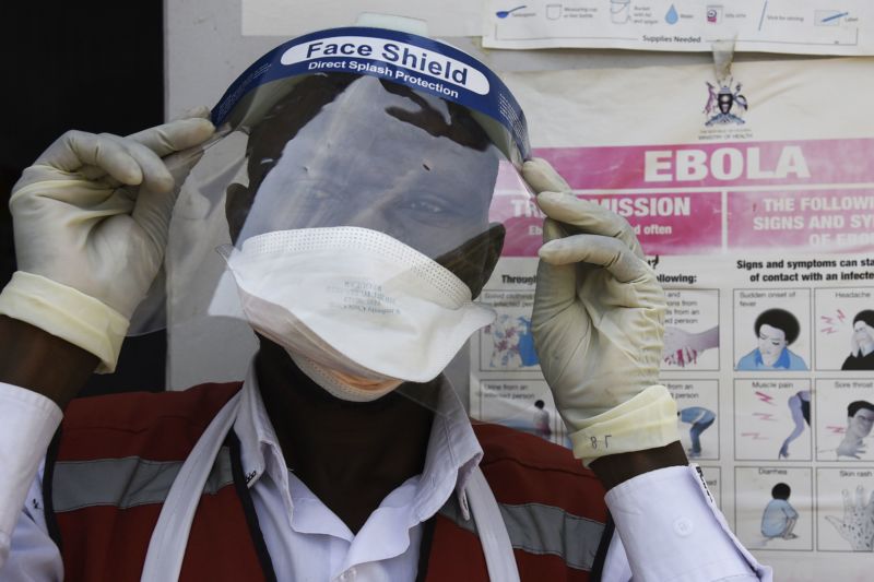 A health worker puts on protective gear as he prepares to screen travelers at the Mpondwe Health Screening Facility in the Ugandan border town of Mpondwe as they cross over from the Democratic Republic of Congo.
