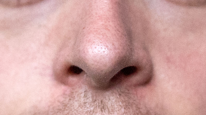 Extreme closeup photograph of a man's nose.