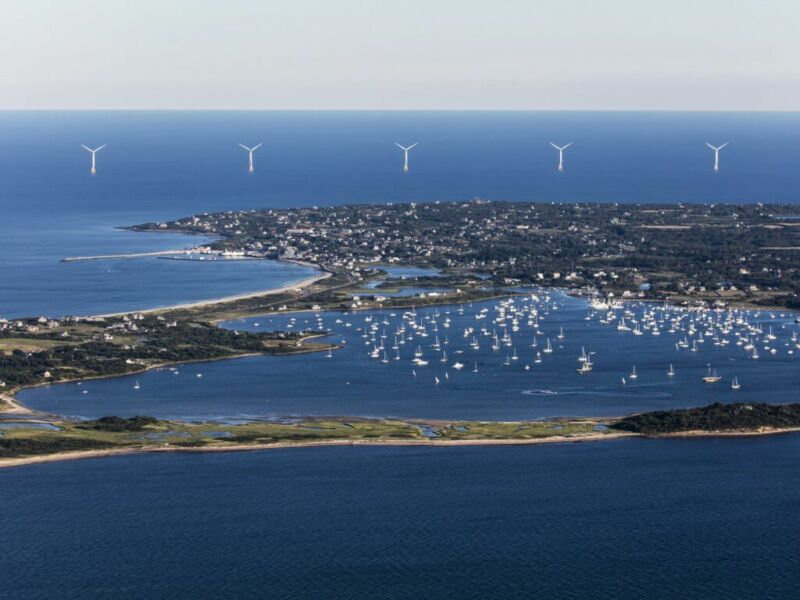 Image of wind turbines in the waters beyond an island.