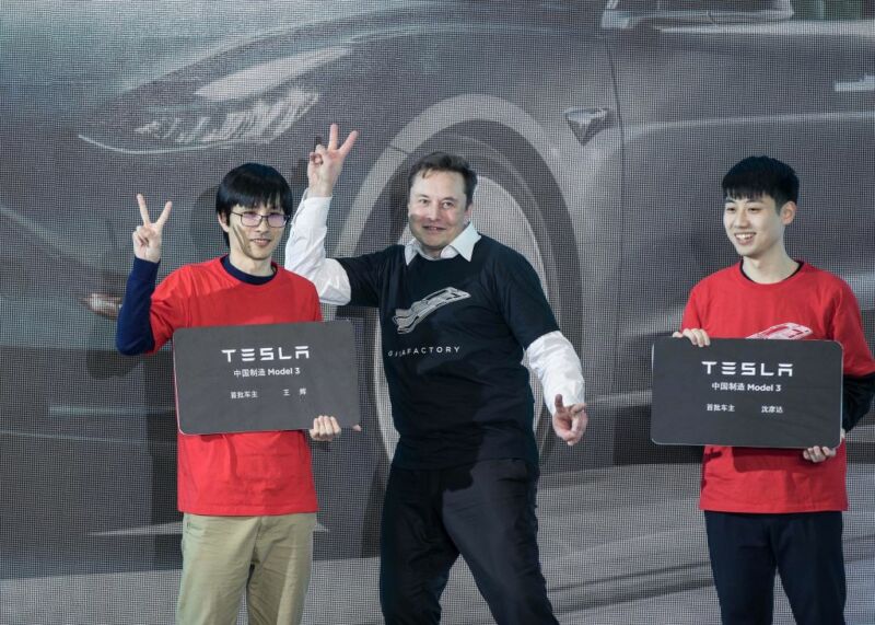 Elon Musk makes a peace sign with two Chinese men.