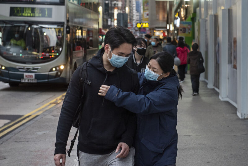 A couple wears ER-style masks on a crowded city street.