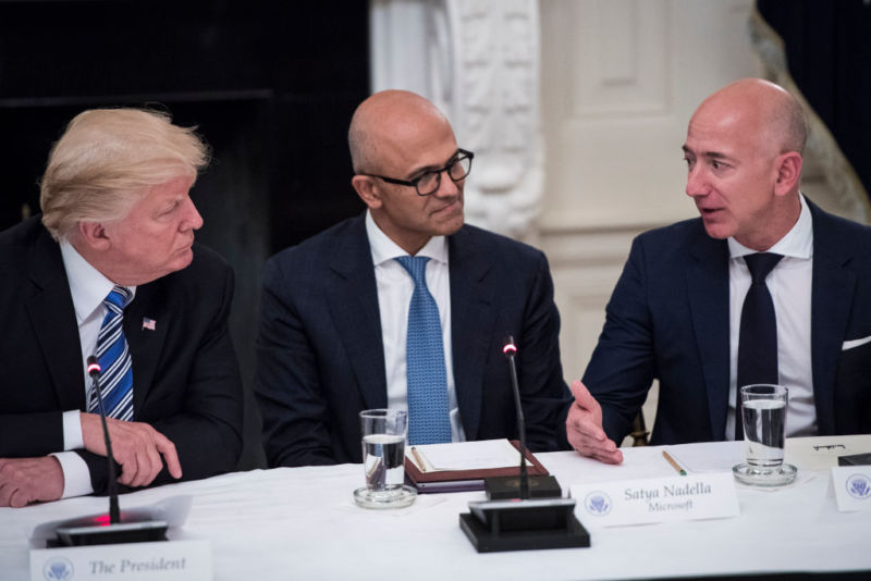 President Donald Trump, Microsoft CEO Satya Nadella, and Amazon CEO Jeff Bezos sit at a table and talk.