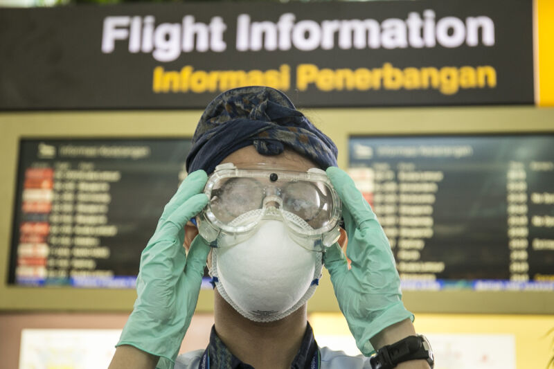 A person stares ominously at camera while putting on goggles.