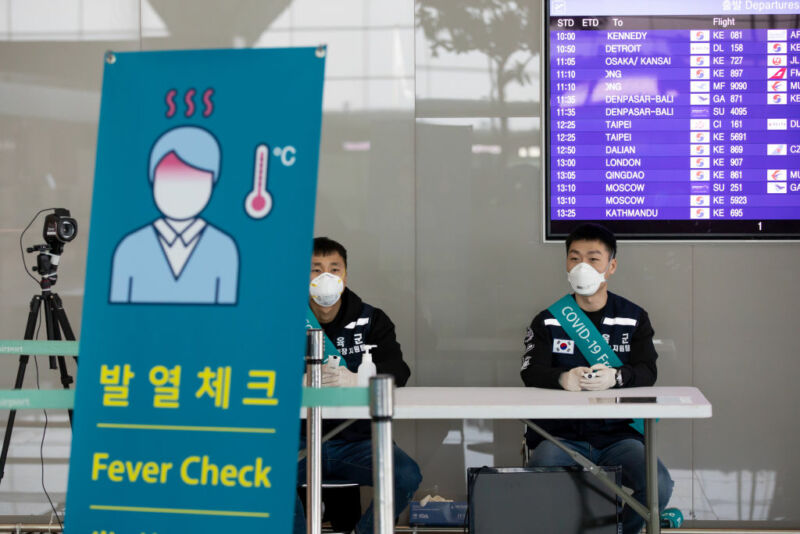South Korean soldiers wearing protective masks sit at a temperature screening point at Incheon International Airport in Incheon, South Korea, on Monday, March 9, 2020. The coronavirus outbreak in South Korea is showing signs of slowing as the rate of new daily infections falls and health authorities almost finished testing members of a religious sect at the center of the epidemic, the country's health minister said. 