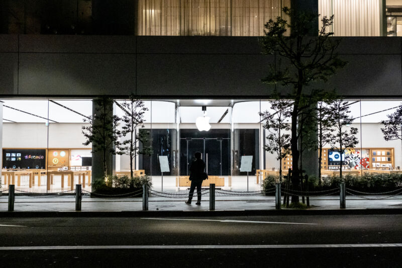 A man stands in front of a closed Apple Store in Tokyo.