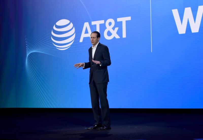 AT&T CEO Randall Stephenson standing and speaking on a stage in front of a big AT&T logo.