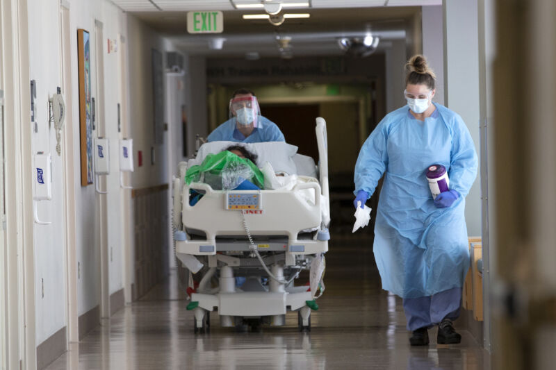 A nurse on infection control accompanies a patient being transferred from the ICU COVID unit to the acute care COVID unit at Harborview Medical Center on May 7, 2020 in Seattle, Washington.