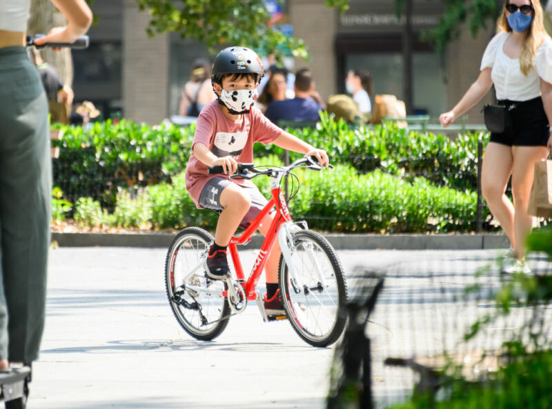 Image of a child wearing a face mask and riding a bicycle.