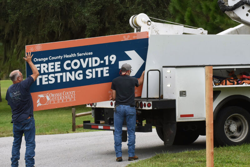 Workers removing a sign from a drive-through COVID-19 testing site in Orlando, Fla. in October, 2020.
