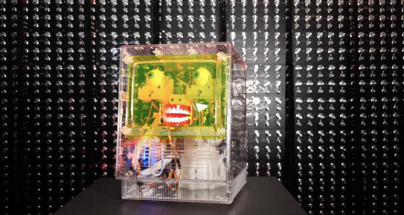 furby facial recognition robot in a clear case in front of a dark background
