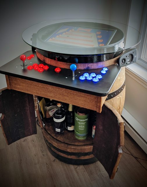 A beer barrel with drinks inside two opening doors cut into the front of the barrel and a retro arcade console serving as the lid of the barrel with joystick and buttons on a ledge in front