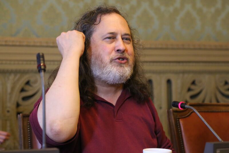 Richard Stallman speaking to an audience while seated at a table.