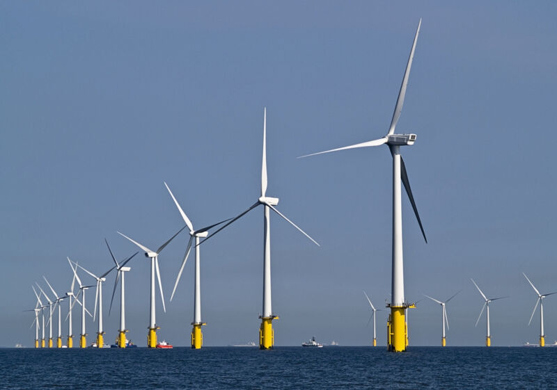 Image of a row of wind turbines in the ocean.
