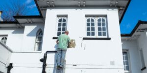 a man painting a house white