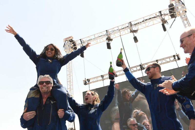 Virgin Galactic founder Sir Richard Branson, with Sirisha Bandla on his shoulders, cheers with crew members after flying into space aboard VSS <em>Unity</em>.