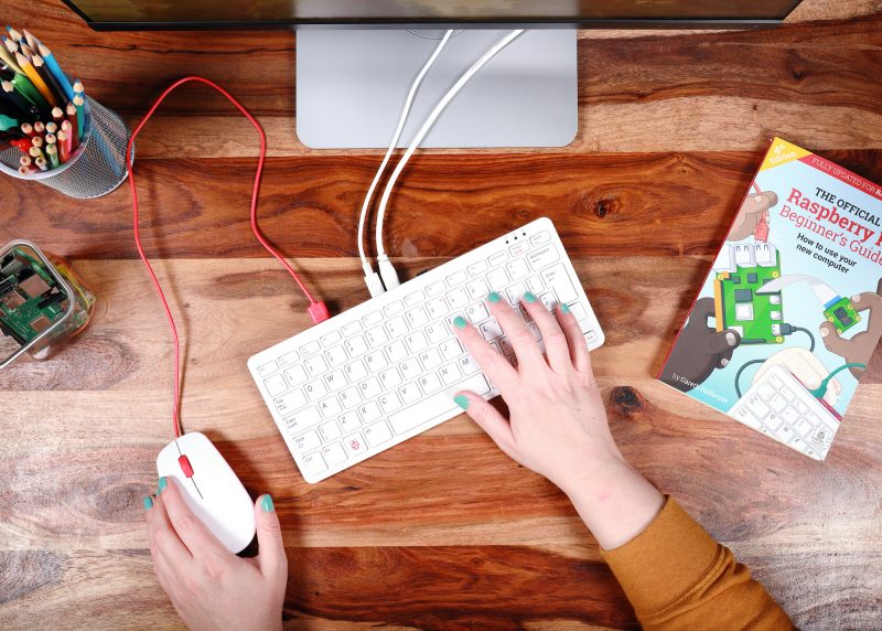 Top view of a woman's hands using the Raspberry Pi 400 keyboard and official Raspberry Pi mouse