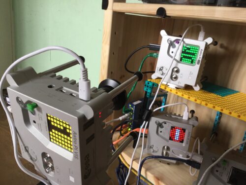Three replica Astro Pi units on a wooden shelf.