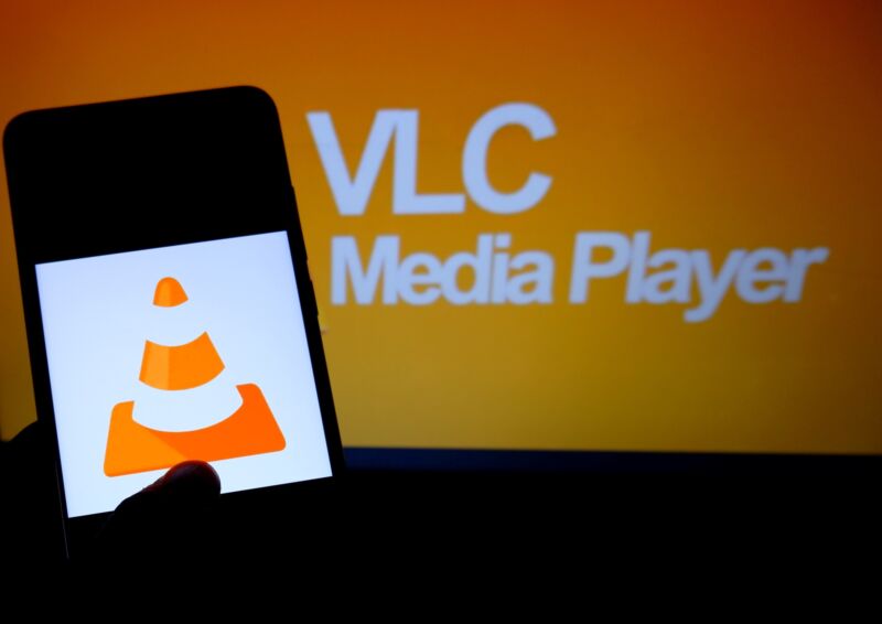 The VLC icon, a traffic cone, is displayed on a smartphone screen with the words 