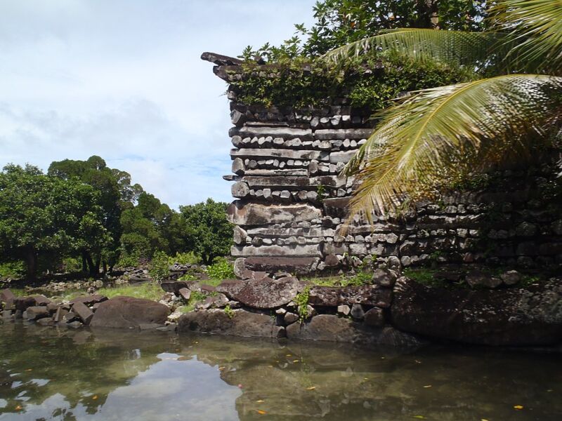 A building constructed of dark stones situated above a water filled channel.