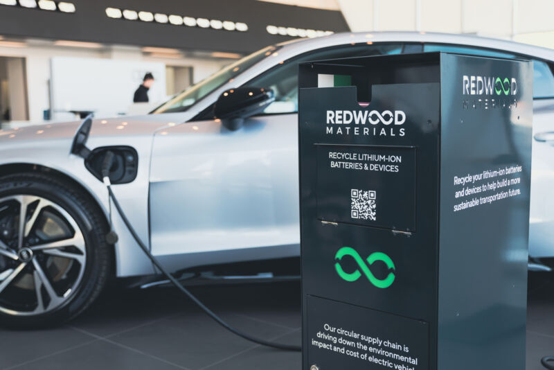 A battery collection box sits in front of an electric Audi at a dealership