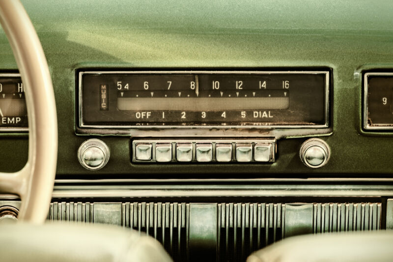 Retro styled image of an old car radio inside a green classic car
