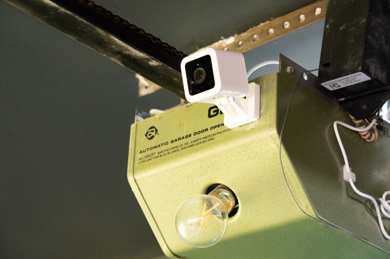 A green garage door opener with a white camera stuck to the front of it.
