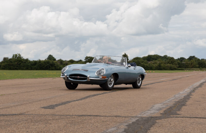 A man drives a blue Jaguar E-Type convertible