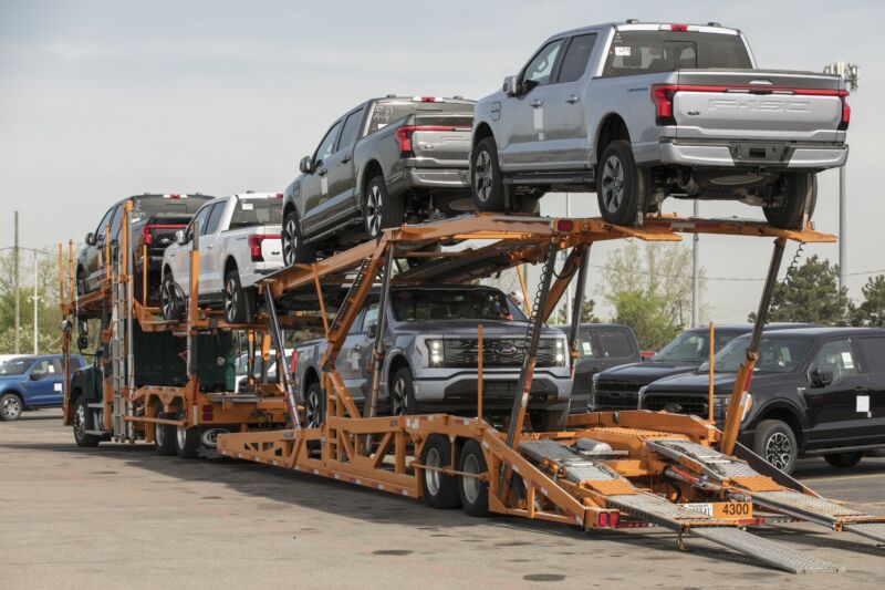 Five Ford F-150 Lightning pickup trucks on a car transporter