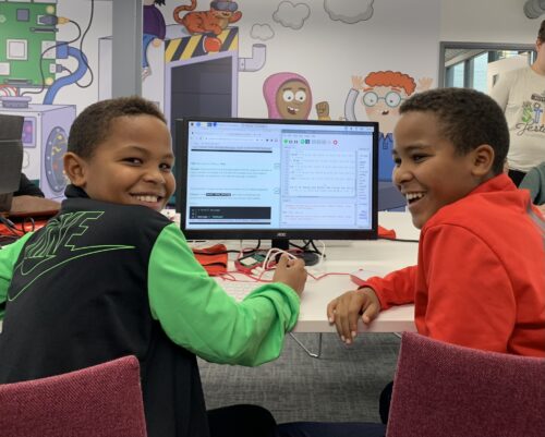 Two kids show off their Python projects in the Code Editor.