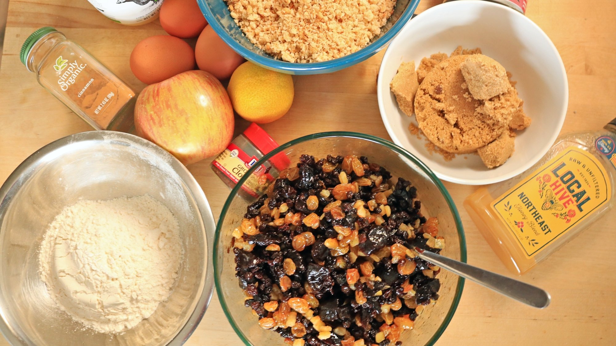 Cake ingredients dried fruit, sugar, and butter on a table.