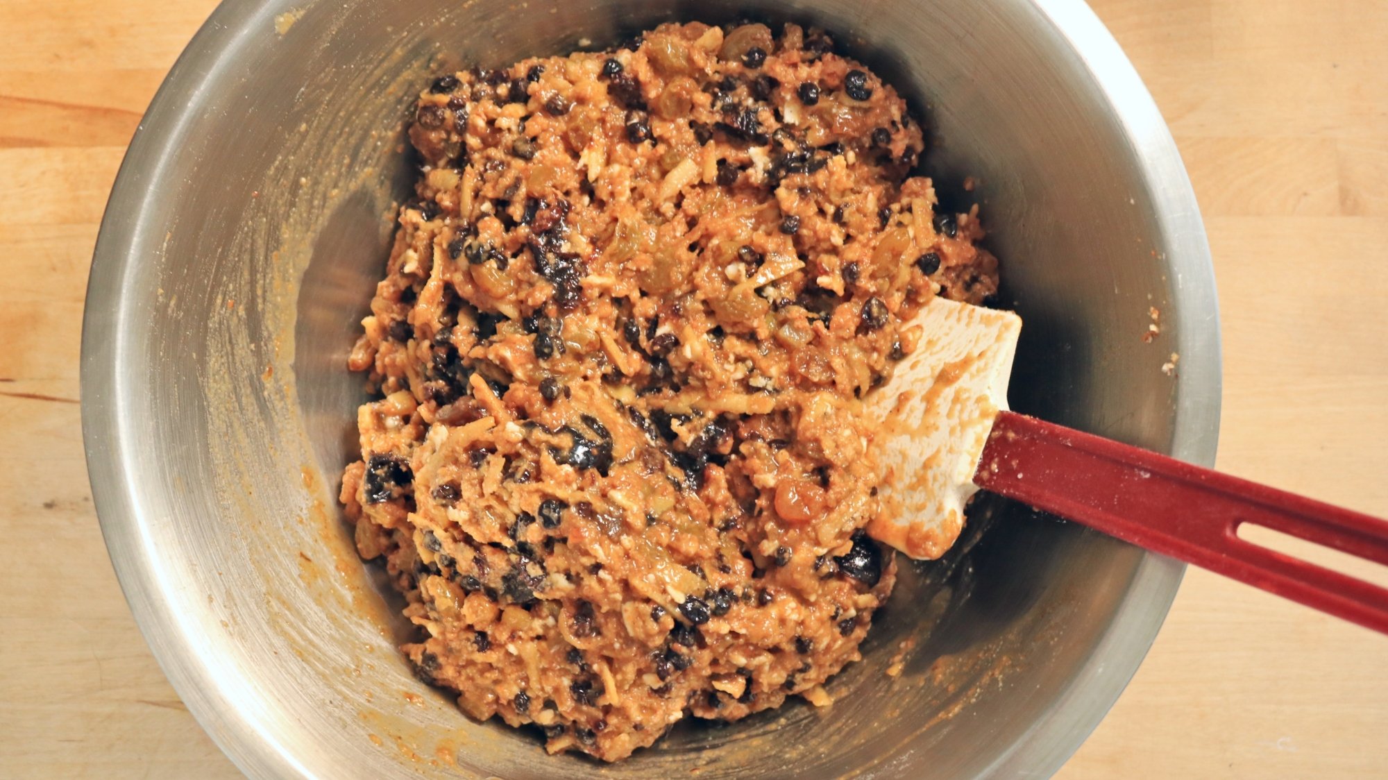 Fruit cake batter in a bowl with a spatula.