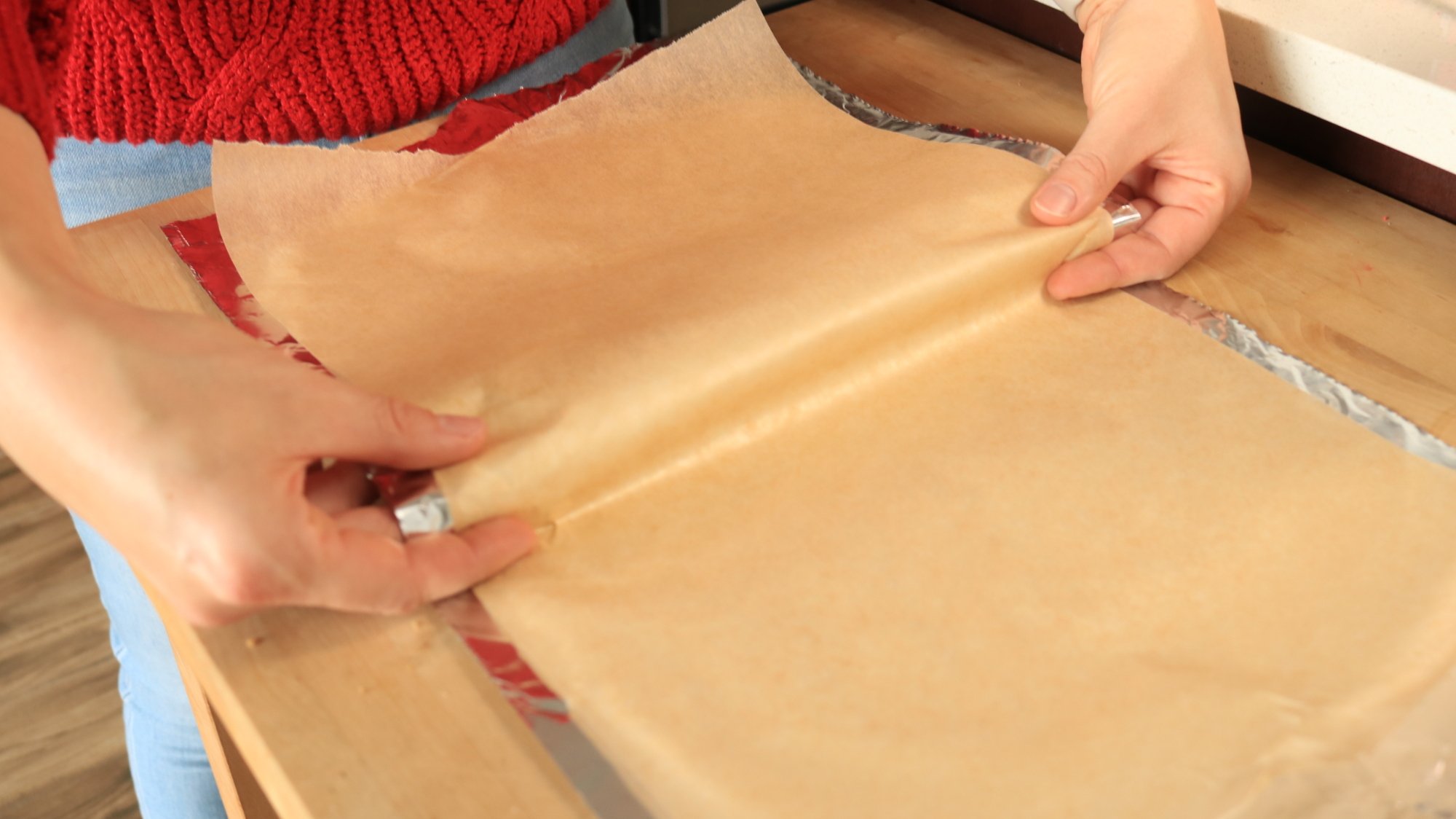Hands folding parchment paper.