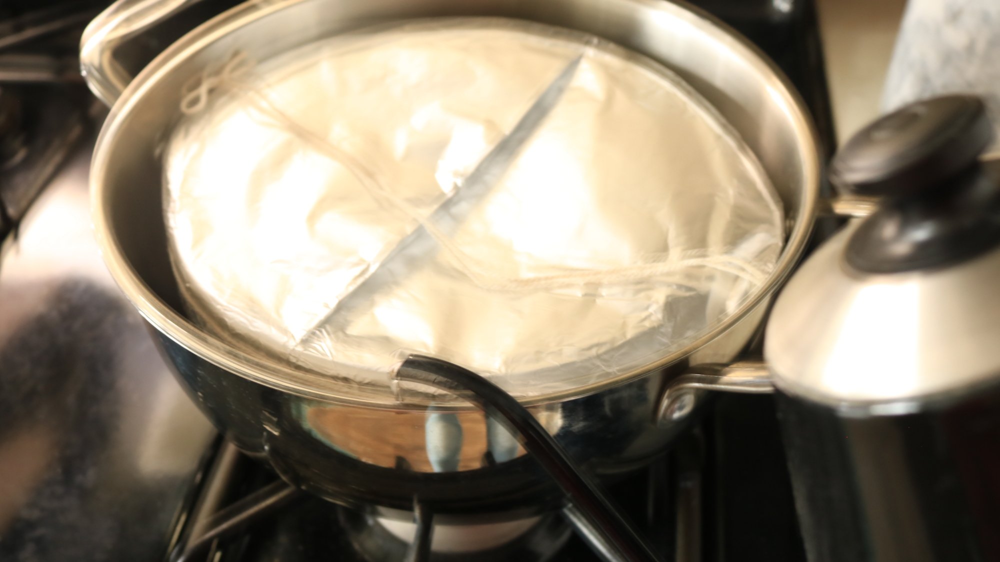 A foil covered bowl in a pot.