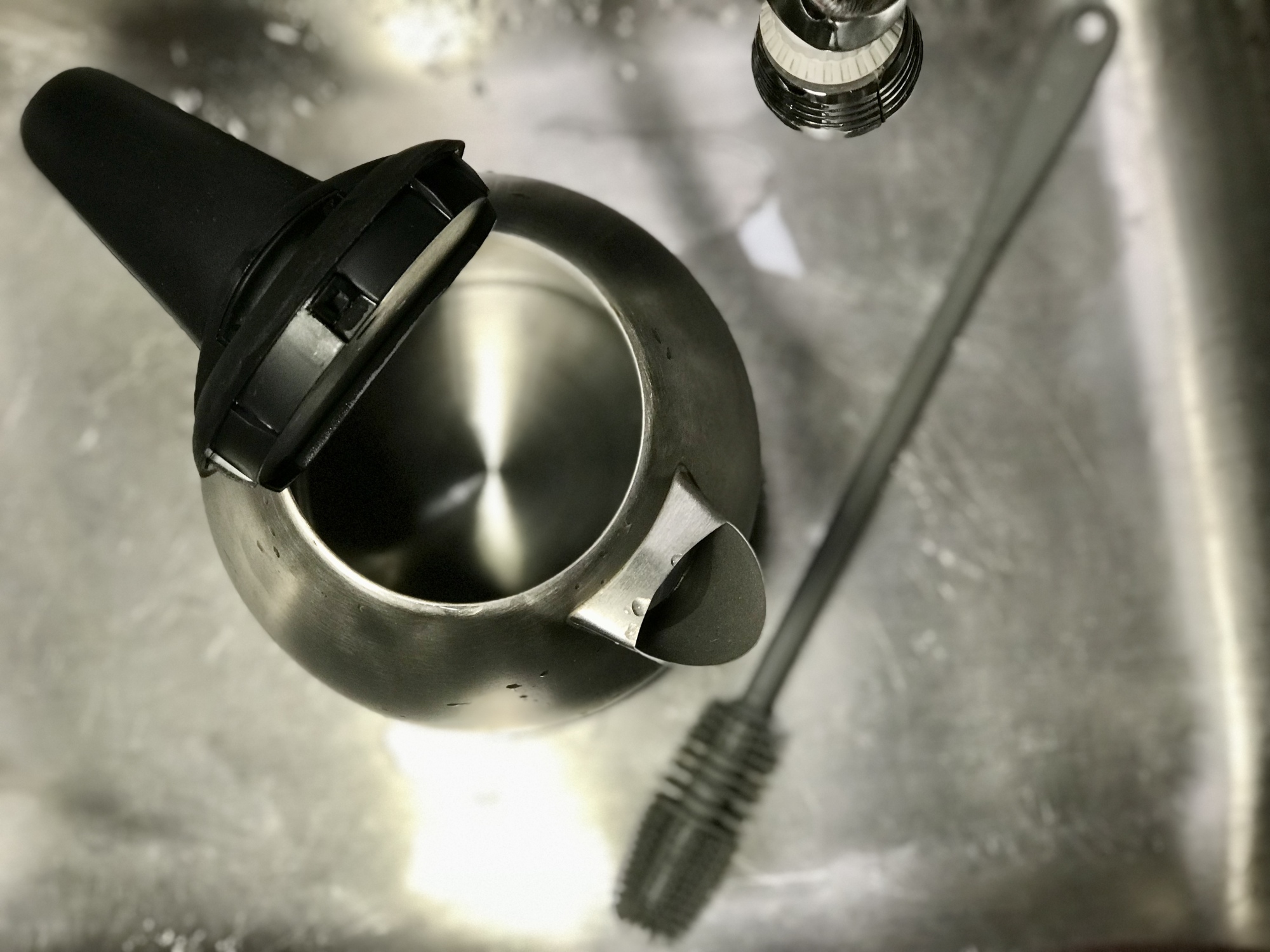 clean open stainless steel electric kettle in sink next to bottle brush