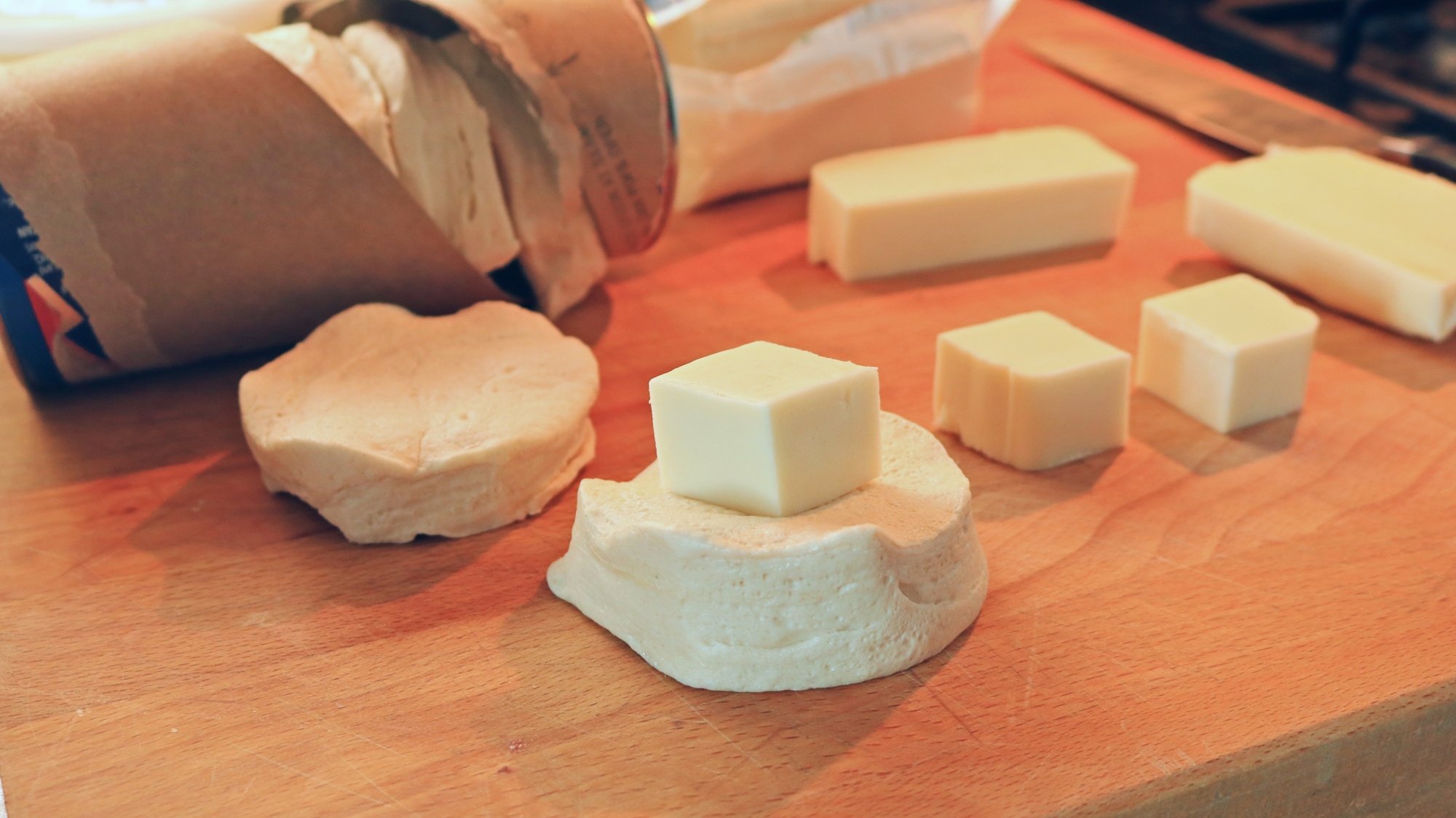 A cube of cheese on top of a raw biscuit.