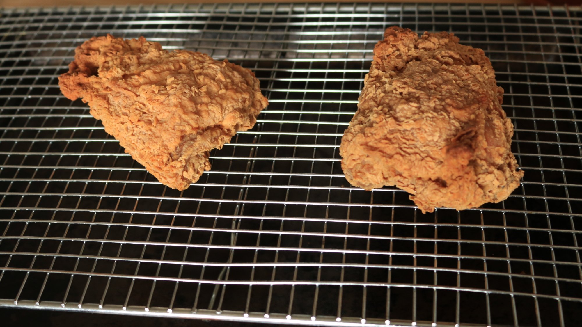 Two piece of fried chicken on a wire rack