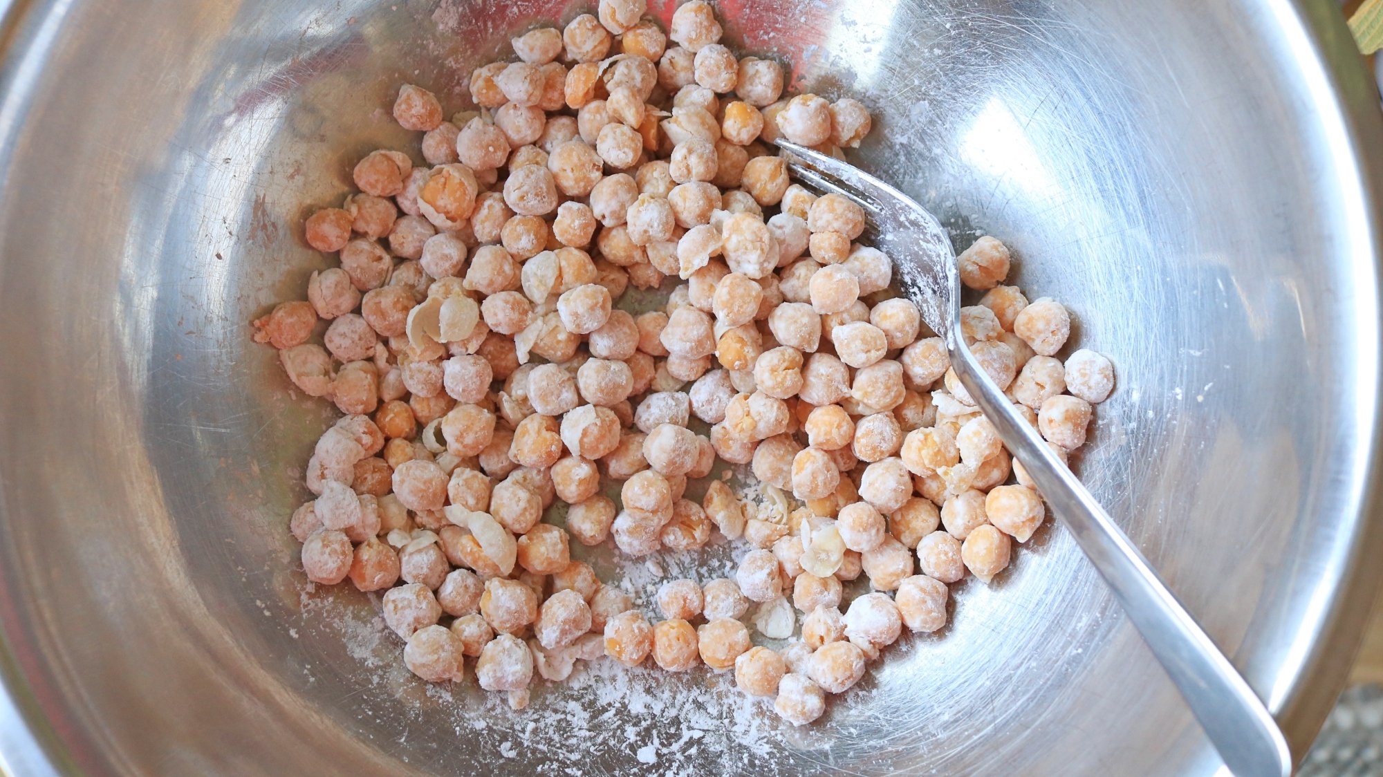 Chickpeas in a bowl tossed with white powdered cornstarch.