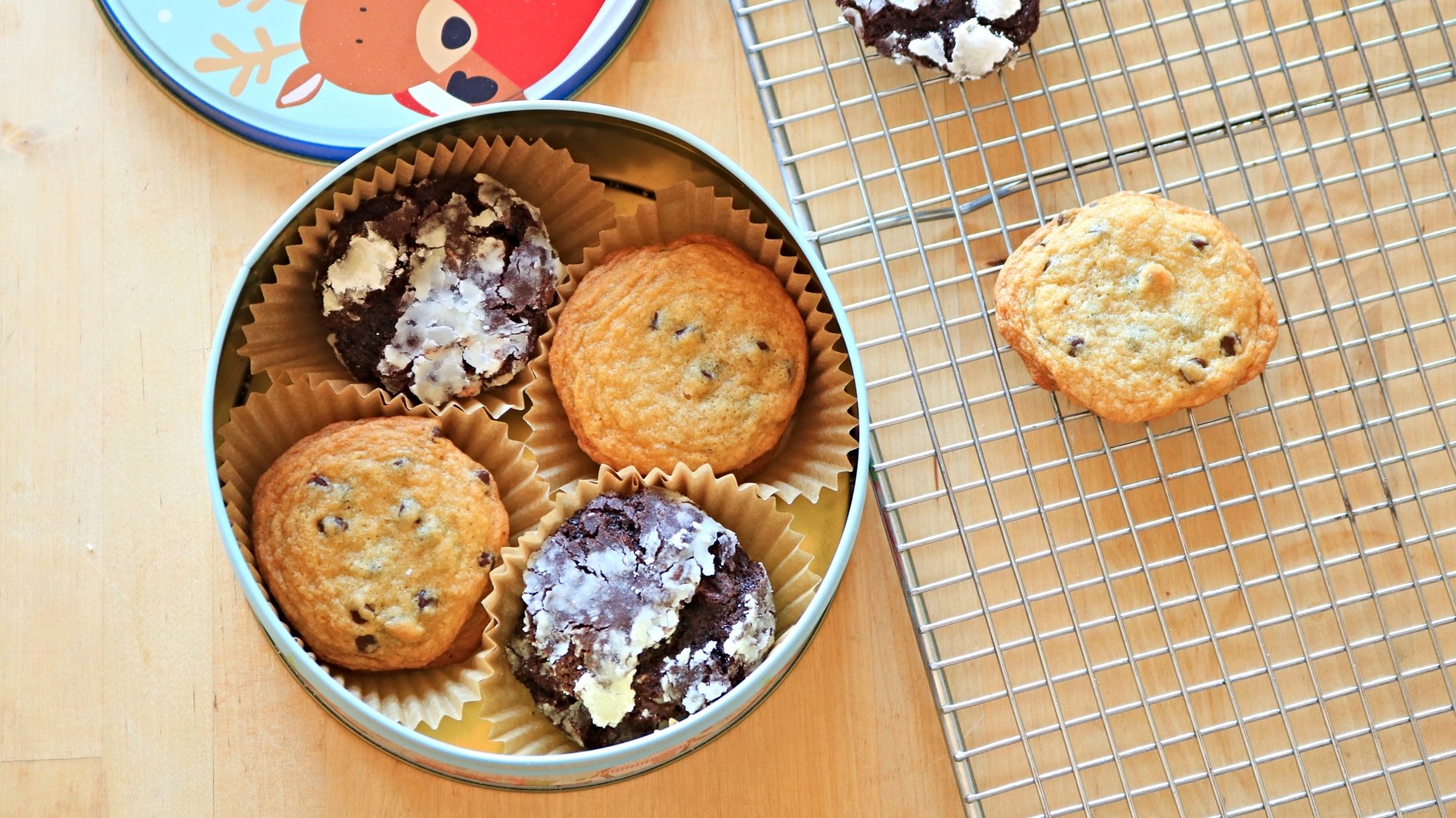 Cookies in a tin next to a wire rack.