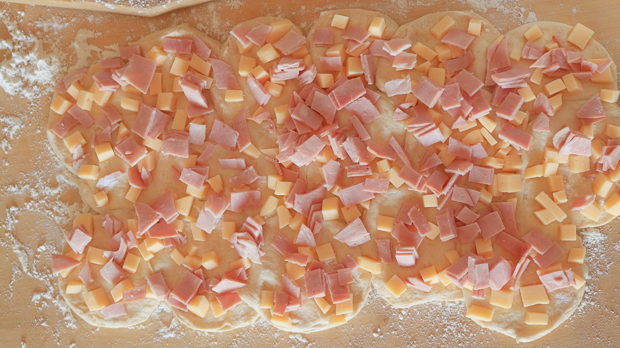 Ham and cheese sprinkled on raw biscuit dough.