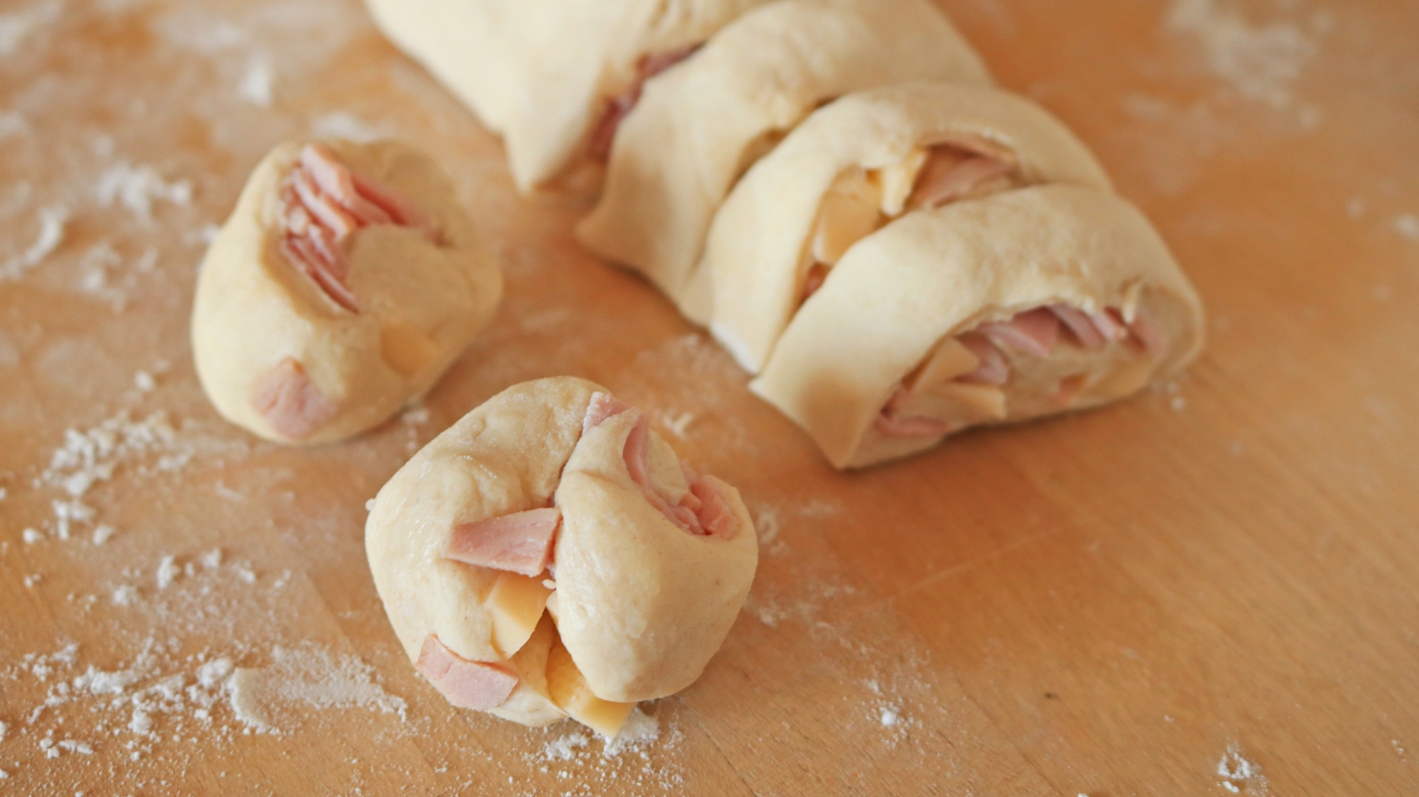 Sliced segments of raw dough with ham and cheese filling.