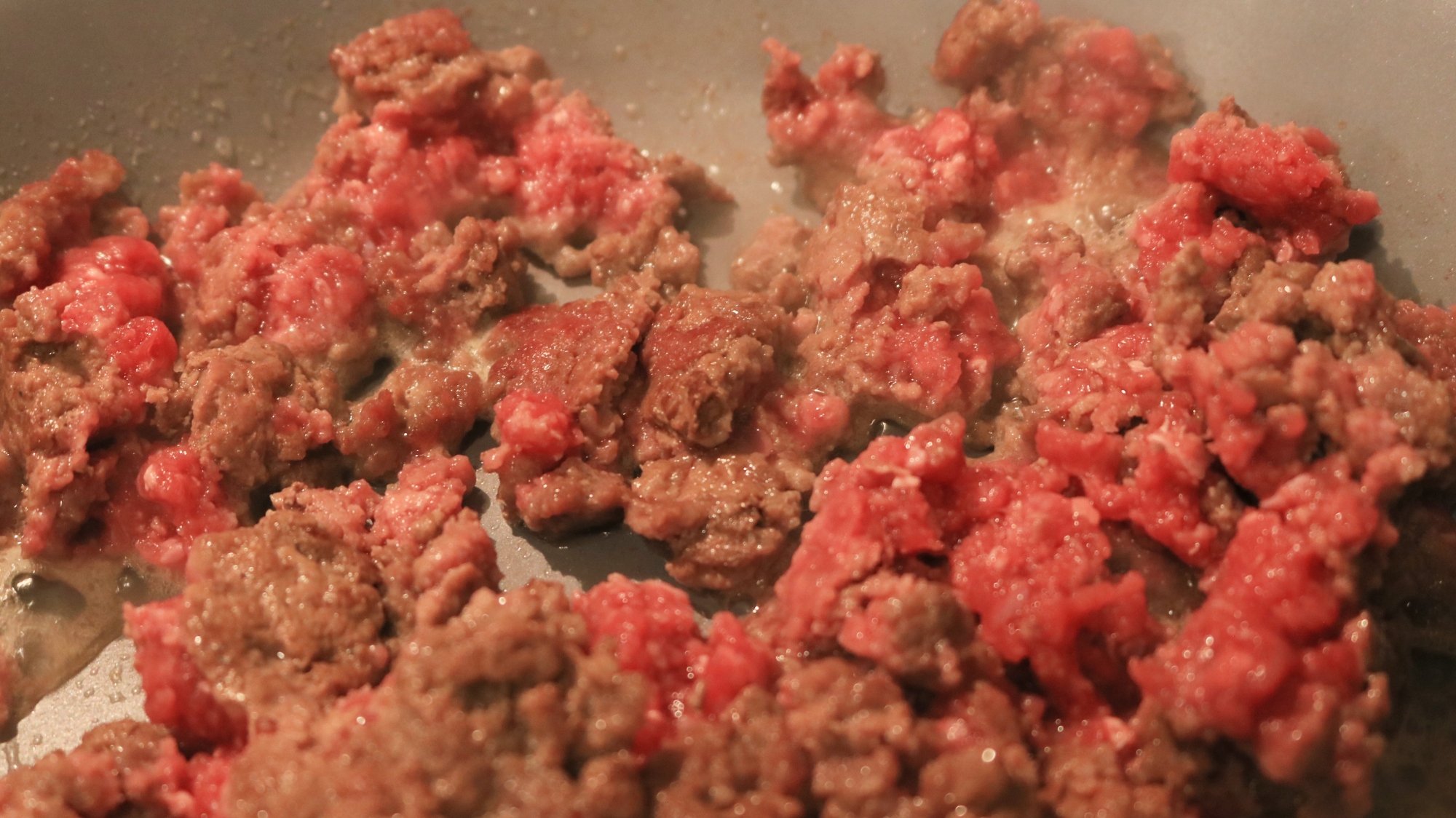 Ground beef browning in a pan.