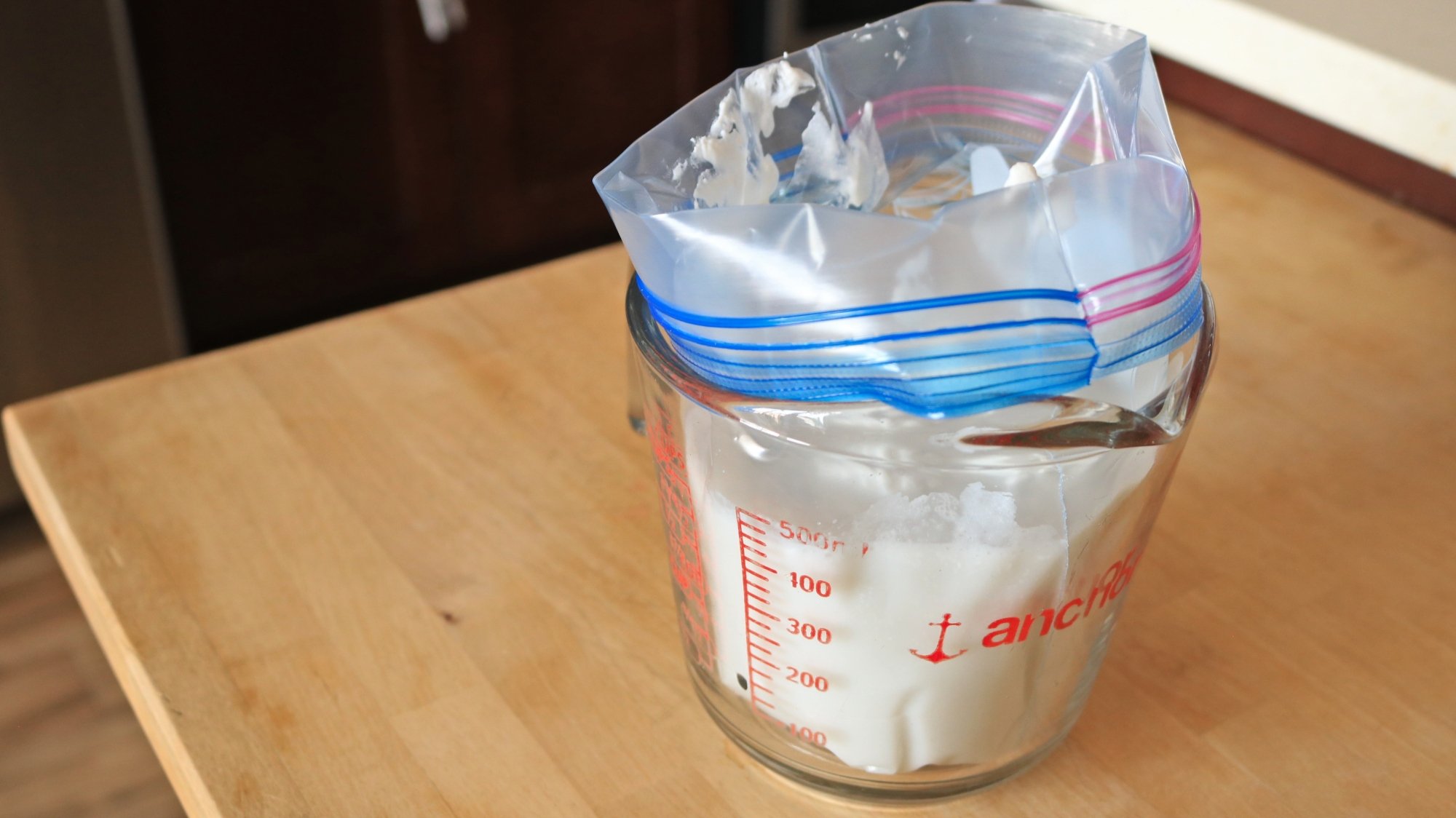 A zip-top bag full of coconut milk in a measuring cup.