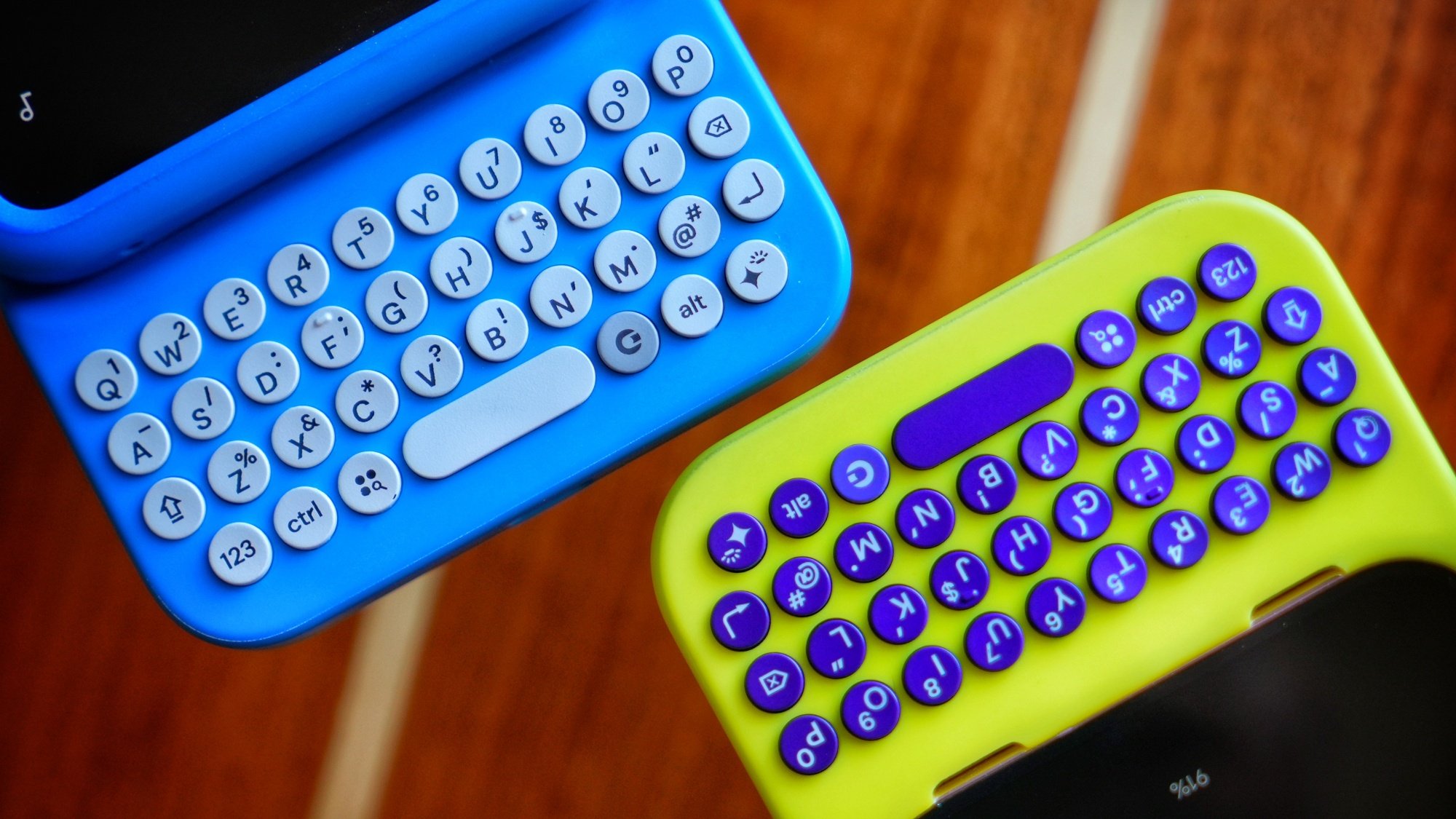 A close-up view of two keyboards by Clicks. One is blue and the other is yellow.