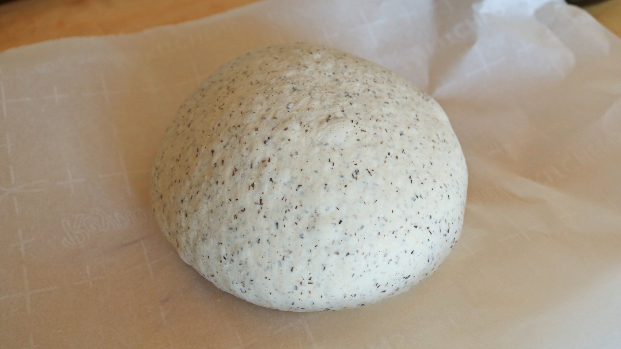 A ball of bread dough on parchment paper.