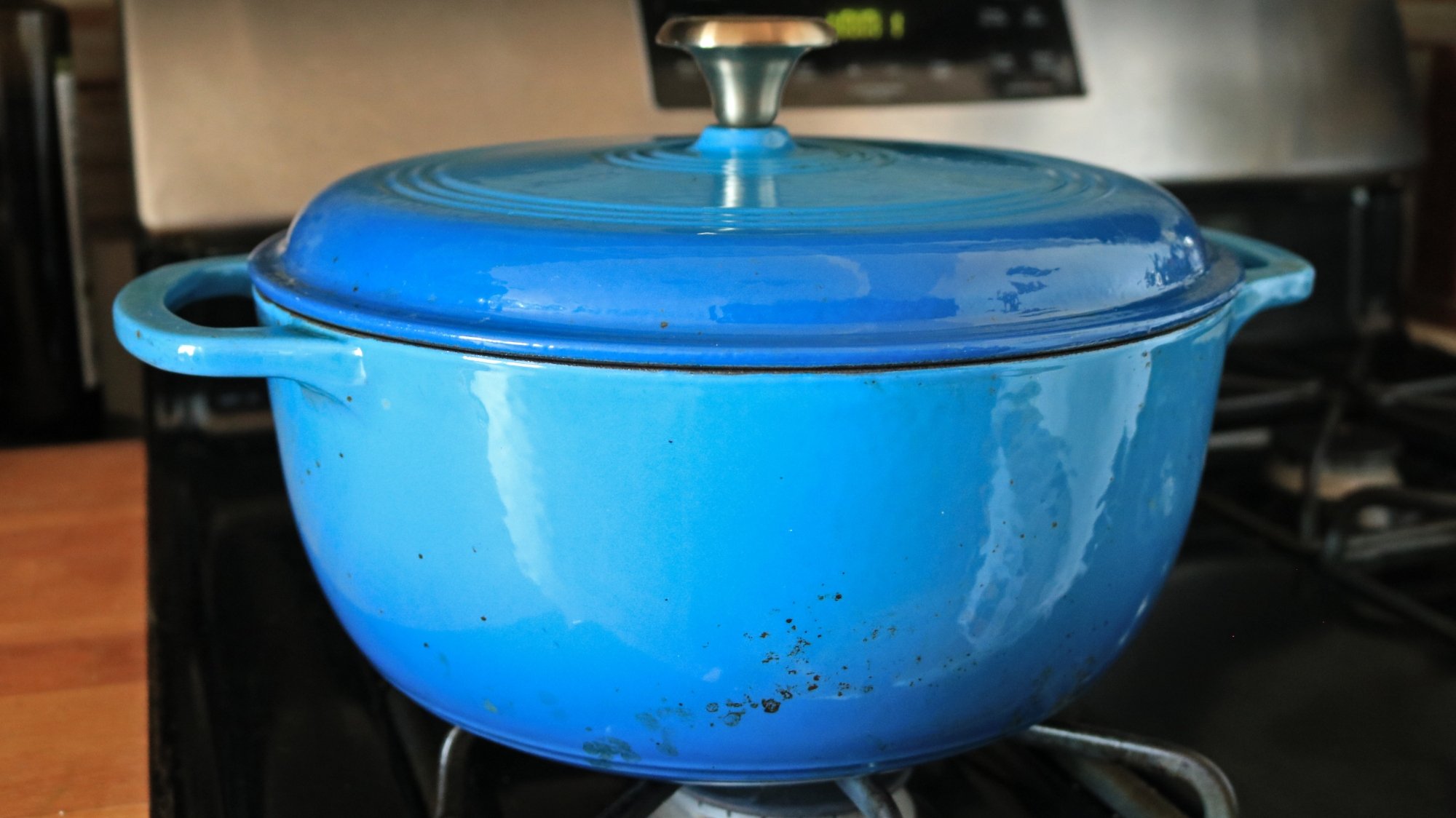 A blue Dutch oven on a stove.