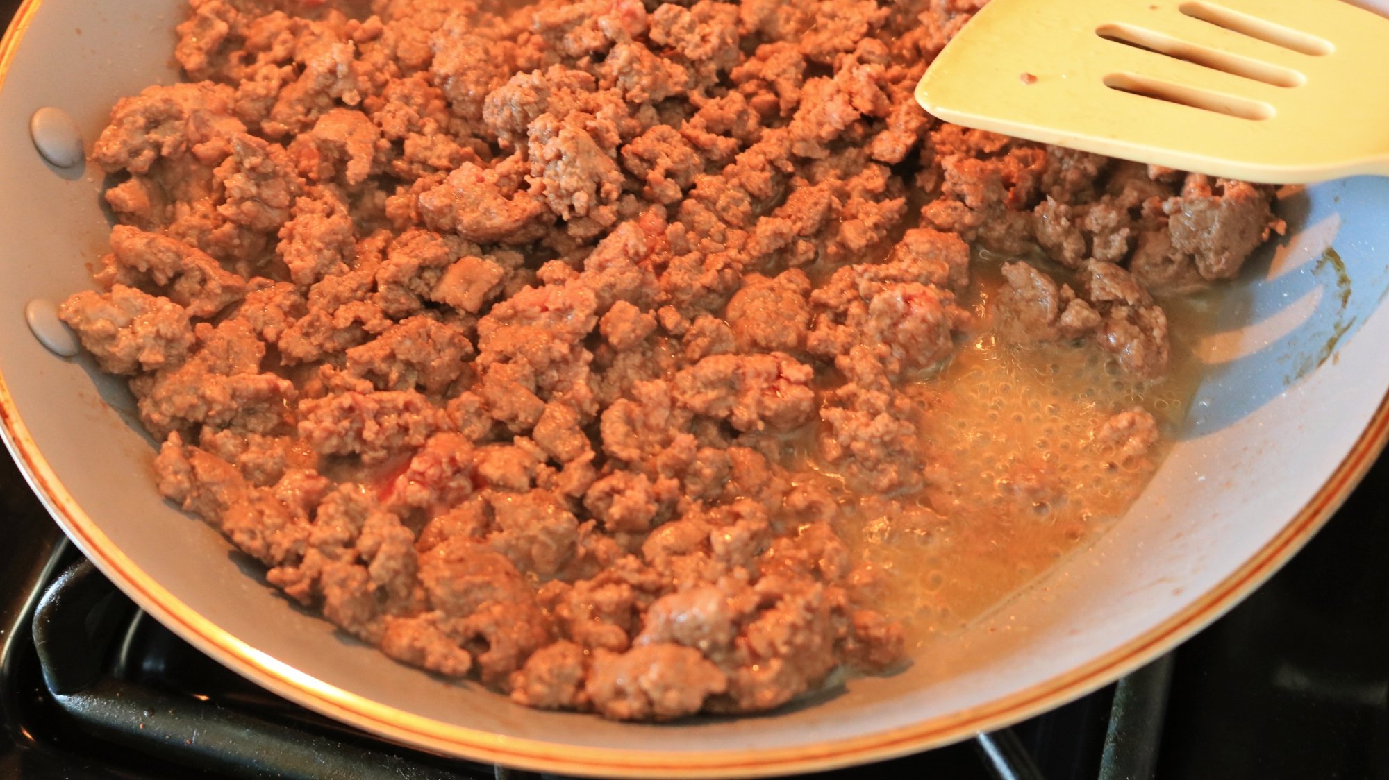Ground beef with liquid in a pan.